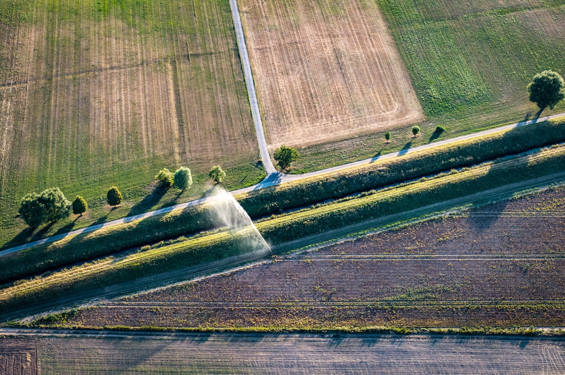 Aerial view of agricultural fields, irrigation ditch, and sprinkler.