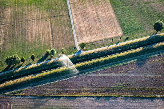 Aerial view of agricultural fields, irrigation ditch, and sprinkler.